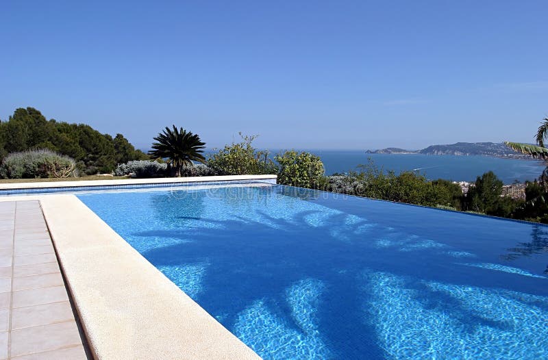 Bella piscina fresca blu di infinità in una villa in Spagna piena di sole con le viste del mare fotografia stock libera da diritti