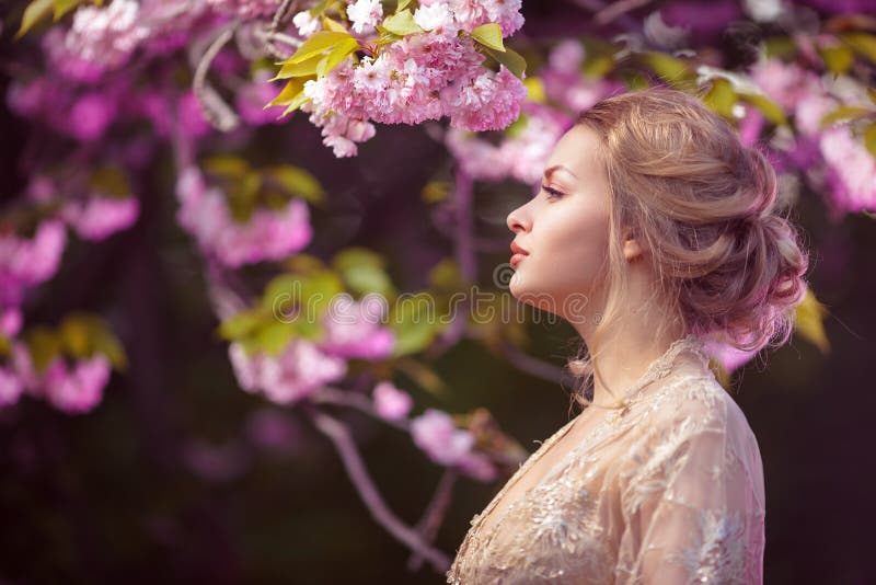 Bella ragazza adulta sexy che sta all'albero sbocciante nel giardino fotografia stock Bella ragazza adulta sexy che sta all'albero sbocciante nel giardino fotografia stock