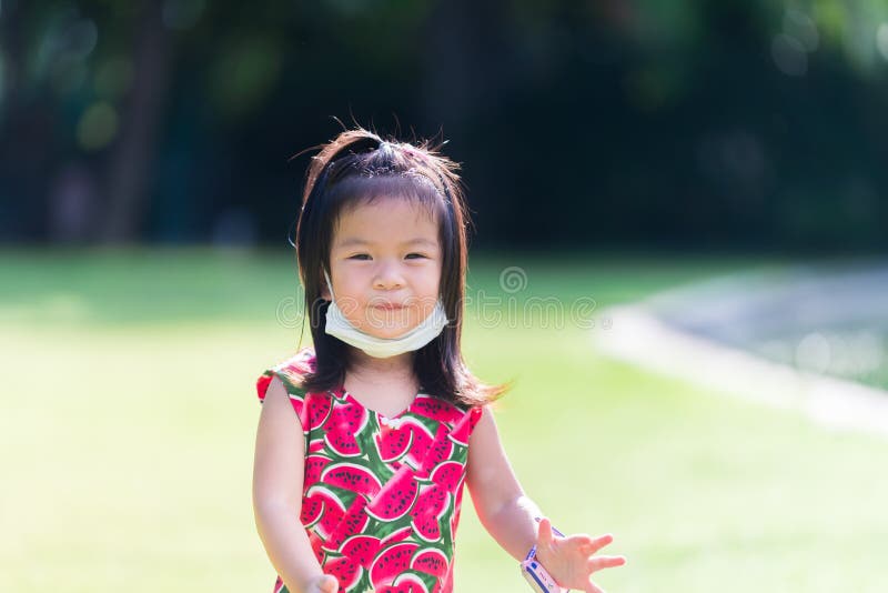 Bella ragazza asiatica. il bambino mascherato sotto il mento. sfondo verde chiaro. estate o primavera. fotografia stock libera da diritti