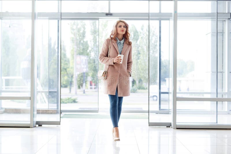 Bella ragazza bionda in bello cappotto beige, jeans e tacchi alti immagine stock libera da diritti Bella ragazza bionda in bello cappotto beige, jeans e tacchi alti immagine stock libera da diritti