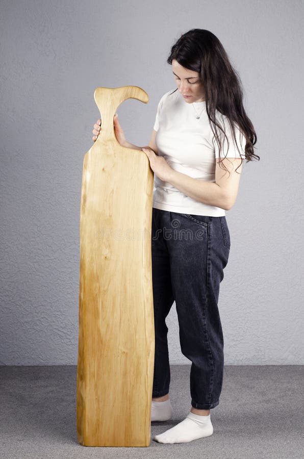 Una donna è in piedi in una cucina con un tavolo di legno e tiene in mano  un accendino.