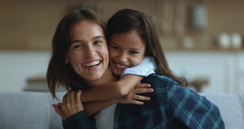 Bella ragazza che abbraccia la giovane mamma felice da dietro