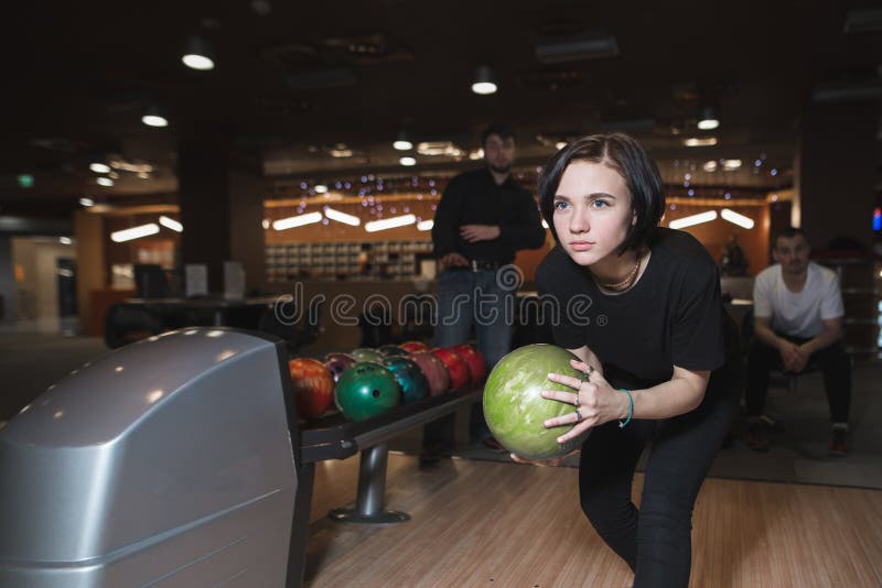 Bella ragazza che gioca bowling Donna con la palla per lanciare in mani nel moto fotografie stock libere da diritti Bella ragazza che gioca bowling Donna con la palla per lanciare in mani nel moto fotografie stock libere da diritti