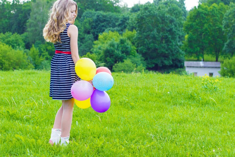 Bella ragazza che gioca con i palloni variopinti nel giorno di estate contro il cielo blu fotografia stock Bella ragazza che gioca con i palloni variopinti nel giorno di estate contro il cielo blu fotografia stock