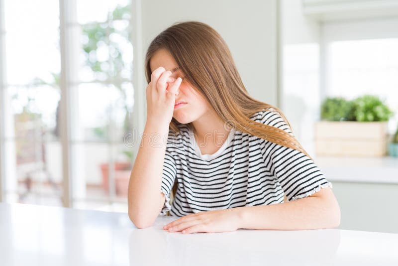 Bella ragazza che indossa strisce camicia stanca di strofinare il naso e gli occhi sentendo fatica e mal di testa fotografia stock