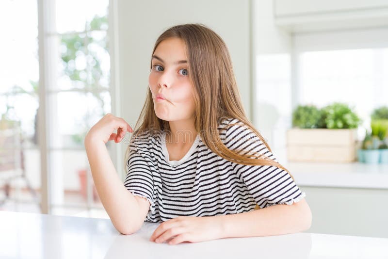 Bella ragazza che indossa una camicia a strisce che fa il pesce con le labbra un gesto comico e folle fotografia stock libera da diritti
