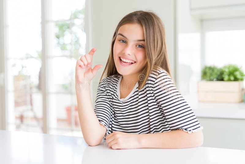 Bella ragazza che indossa una camicia a strisce che sorride e un gesto sicuro con la mano che fa un cartello con le dita mentre fotografia stock