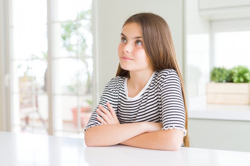 Bella ragazza che indossa una camicia a strisce che sorride guardando da un lato e guardandosi dall'altro pensando fotografie stock