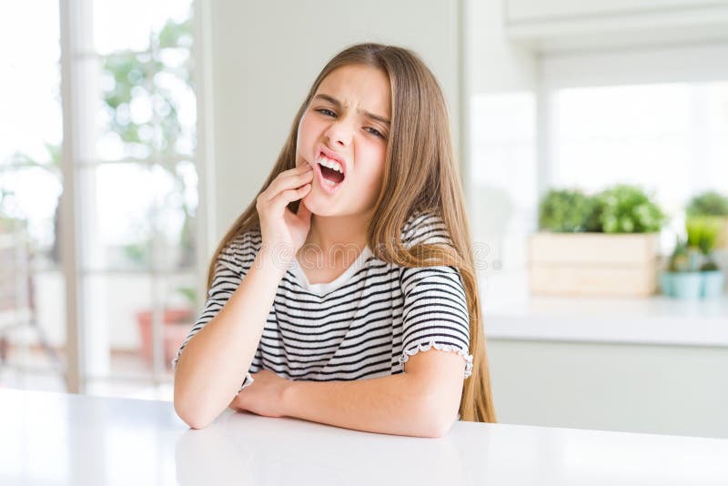 Bella ragazza che indossa una camicia a strisce che tocca la bocca con la mano con un'espressione dolorosa a causa del mal di dent immagini stock