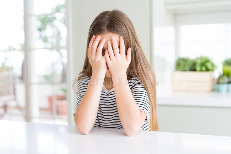 Bella ragazza che indossa una maglietta con una triste espressione che copre il viso con le mani in lacrime immagine stock libera da diritti