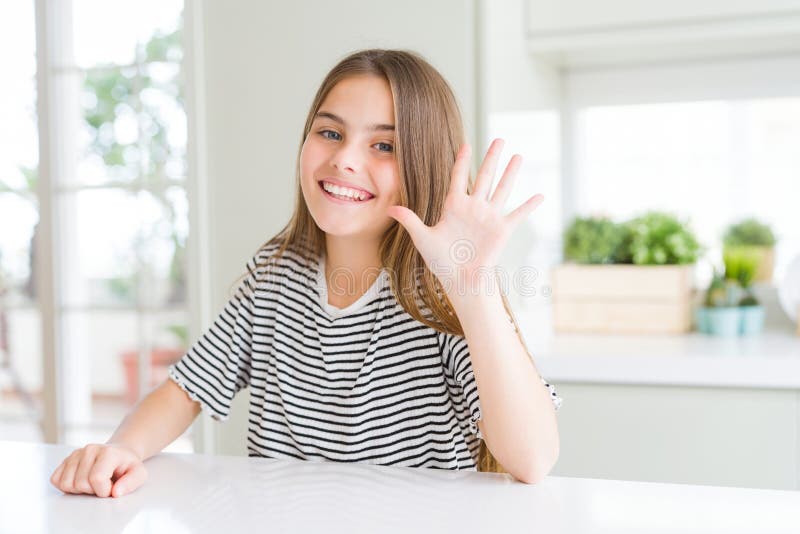 Bella ragazza che indossa una maglietta a strisce che mostra e punta con le dita numero cinque mentre sorride sicura di sé e fotografie stock libere da diritti