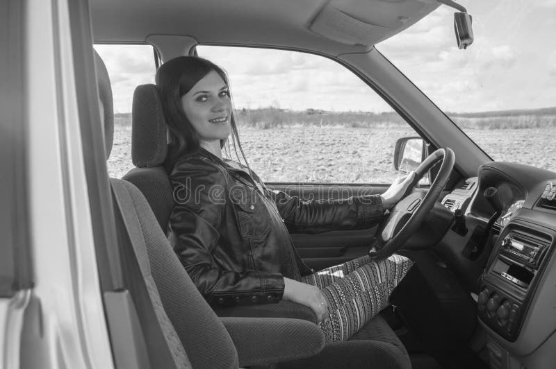 Bella ragazza che si siede nell'automobile, in bianco e nero fotografia stock Bella ragazza che si siede nell'automobile, in bianco e nero fotografia stock