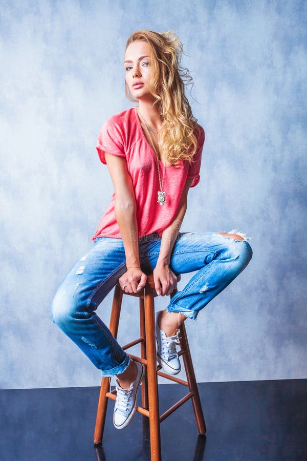 Bella ragazza che si siede su una posa di legno della sedia fotografia stock libera da diritti Bella ragazza che si siede su una posa di legno della sedia fotografia stock libera da diritti