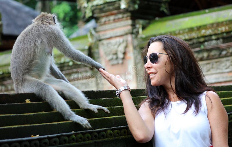Bella ragazza che si tiene per mano con la scimmia alla foresta delle scimmie in Bali Indonesia, donna graziosa con l'animale sel immagini stock Bella ragazza che si tiene per mano con la scimmia alla foresta delle scimmie in Bali Indonesia, donna graziosa con l'animale sel immagini stock