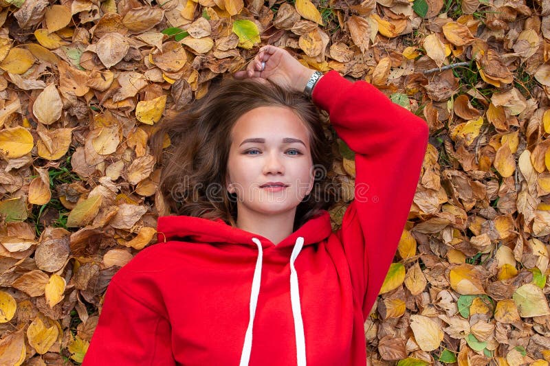 Bella ragazza che si trova sulle foglie di autunno nel parco fotografia stock libera da diritti Bella ragazza che si trova sulle foglie di autunno nel parco fotografia stock libera da diritti