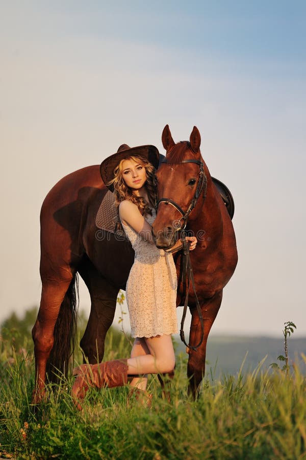 Bella ragazza con il sauro nel campo di sera fotografia stock libera da diritti Bella ragazza con il sauro nel campo di sera fotografia stock libera da diritti
