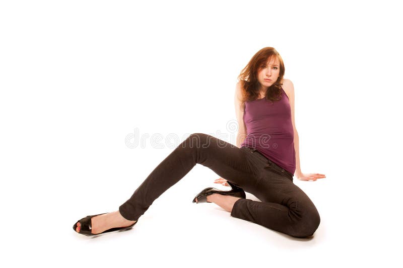 Bella ragazza con jeans neri e tacchi alti seduti in una bella posa sul pavimento