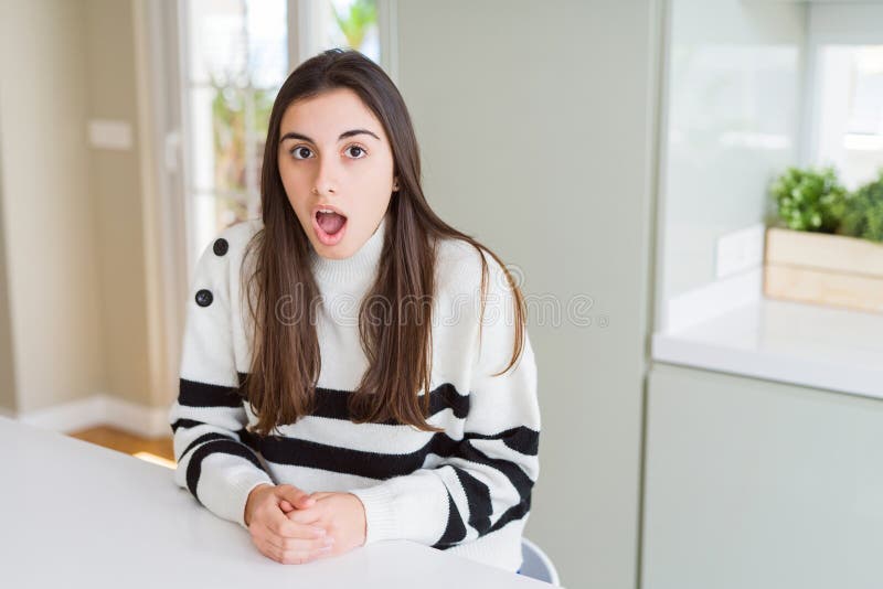 Bella ragazza con strisce maglione spaventata e scioccata dall'espressione sorpresa paura e faccia eccitata fotografie stock libere da diritti