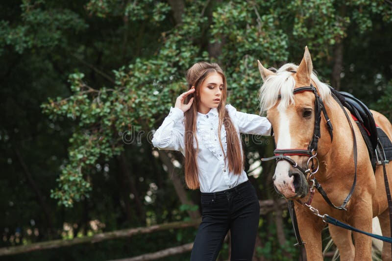 Bella ragazza del ritratto in camicia bianca e pantaloni neri con il cavallo seguente dei capelli lunghi di bellezza in woma alla fotografia stock Bella ragazza del ritratto in camicia bianca e pantaloni neri con il cavallo seguente dei capelli lunghi di bellezza in woma alla fotografia stock