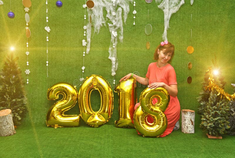 Beautiful pretty girl in dress with numbers of new year 2018 and Christmas trees in new year`s lights Congratulation on a Christmas - concept. Beautiful pretty girl in dress with numbers of new year 2018 and Christmas trees in new year`s lights Congratulation on a Christmas - concept