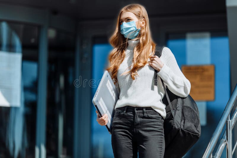 Bella ragazza mascherata da studente coronovirus sullo sfondo dell'invidia per l'istruzione delle donne che tornano dal lavoro immagini stock libere da diritti