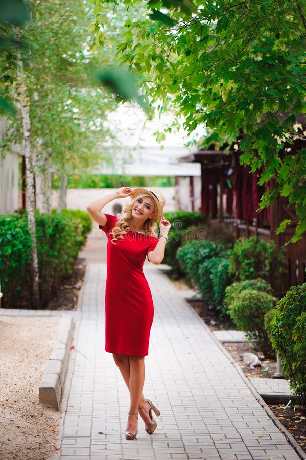 Bella ragazza nel sorriso del vestito elegante e del cappello ed incantare che posa per il fotografo nel parco immagini stock libere da diritti Bella ragazza nel sorriso del vestito elegante e del cappello ed incantare che posa per il fotografo nel parco immagini stock libere da diritti