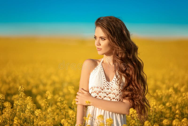 Bella ragazza spensierata con capelli sani ricci lunghi sopra il fondo giallo del paesaggio del campo della violenza Attracive ca