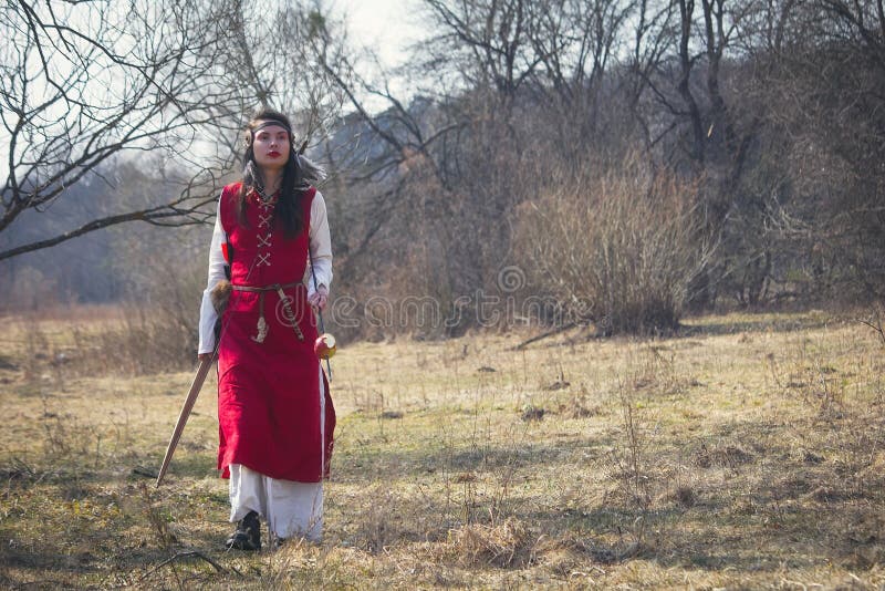 Bella ragazza in vestito medievale rosso che cammina il prato fotografia stock libera da diritti Bella ragazza in vestito medievale rosso che cammina il prato fotografia stock libera da diritti