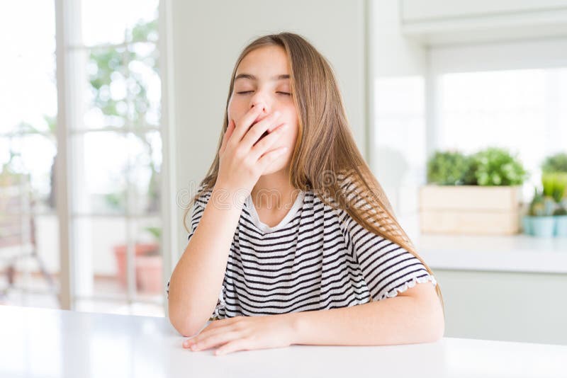 Bella ragazzina con una camicia a strisce annoiata sbadigliando la bocca con la mano fotografie stock