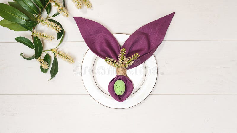 Bella regolazione della tavola di Pasqua con l'uovo, coniglietto di pasqua porpora del tovagliolo, ramo di albero di verde della fotografia stock libera da diritti Bella regolazione della tavola di Pasqua con l'uovo, coniglietto di pasqua porpora del tovagliolo, ramo di albero di verde della fotografia stock libera da diritti