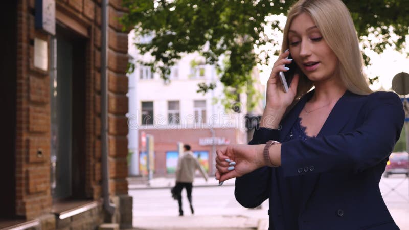 Bella rubia hablando por teléfono con amigos que se regocijan sonriendo dientes blancos afuera se acercan. el