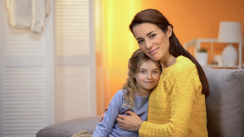 Bella signora sorridente che abbraccia ragazza felice, famiglia che guarda alla macchina fotografica, paternit? fotografia stock libera da diritti Bella signora sorridente che abbraccia ragazza felice, famiglia che guarda alla macchina fotografica, paternit? fotografia stock libera da diritti