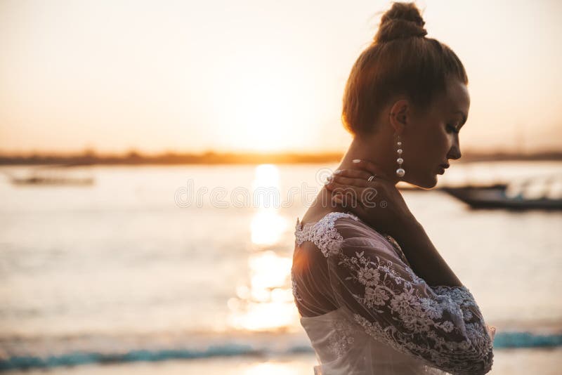 Bella sposa che posa sulla spiaggia dietro il mare al tramonto immagine stock libera da diritti Bella sposa che posa sulla spiaggia dietro il mare al tramonto immagine stock libera da diritti
