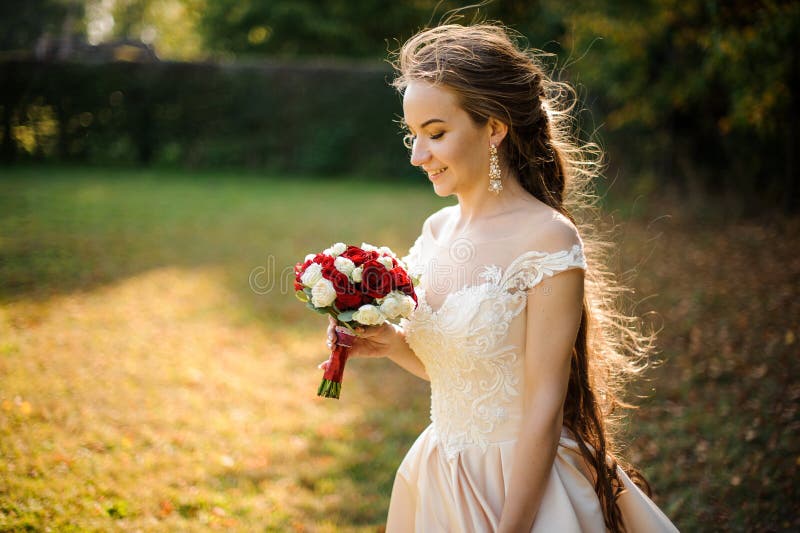 Bella sposa in un vestito da sposa bianco che tiene un mazzo beauriful delle rose rosse immagini stock Bella sposa in un vestito da sposa bianco che tiene un mazzo beauriful delle rose rosse immagini stock