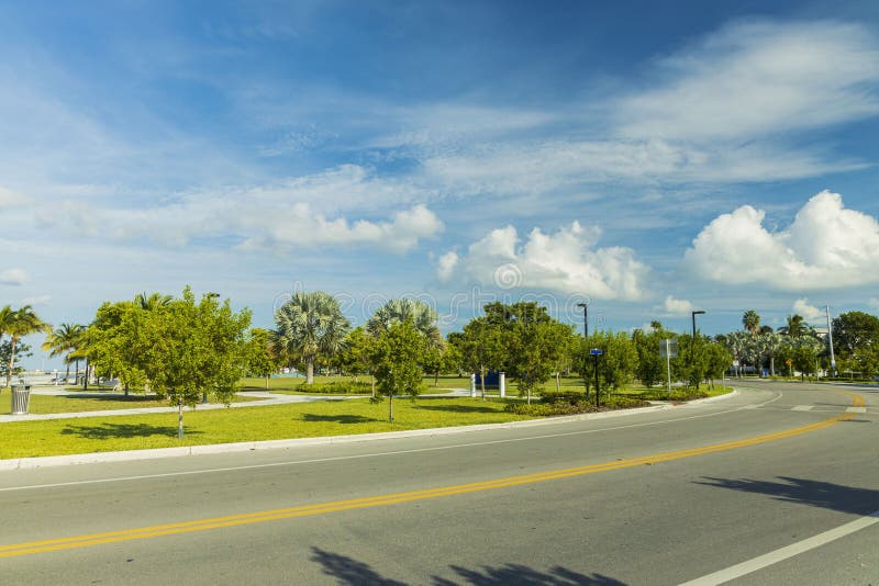 Bella vista del paesaggio urbano Strada di asfalto e alberi verdi tropicali sul cielo azzurro con fondo di nuvole bianche Key Wes fotografie stock Bella vista del paesaggio urbano Strada di asfalto e alberi verdi tropicali sul cielo azzurro con fondo di nuvole bianche Key Wes fotografie stock