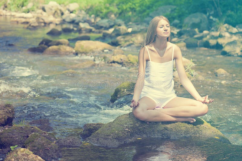 Bella yoga di Practive della donna sul fiume in natura fotografie stock libere da diritti Bella yoga di Practive della donna sul fiume in natura fotografie stock libere da diritti