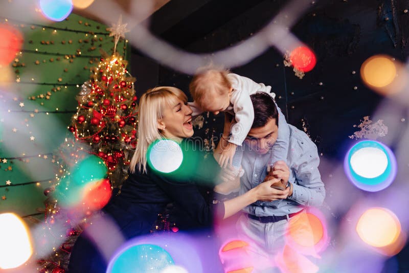 Belle famille avec peu de bébé sur le fond d'un arbre de Noël, célébrant la nouvelle année photographie stock libre de droits Belle famille avec peu de bébé sur le fond d'un arbre de Noël, célébrant la nouvelle année photographie stock libre de droits