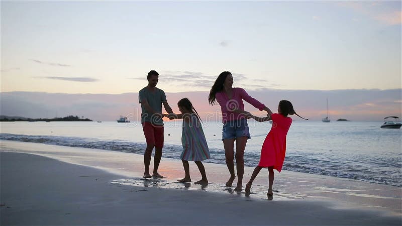 Belle famille heureuse sur une plage pendant des vacances d'été La famille de quatre ont l'amusement au coucher du soleil sur la banque de vidéos