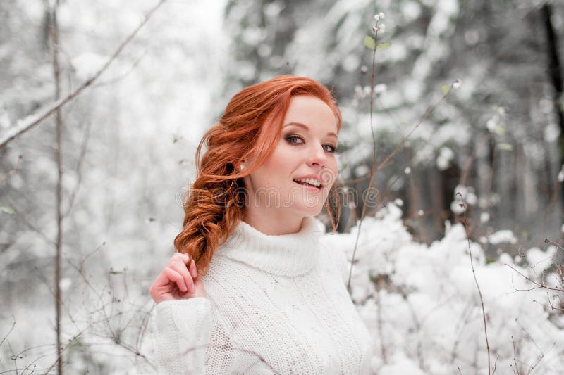Belle femelle de gingembre dans le chandail blanc dans la neige décembre de forêt d'hiver en parc Portrait Temps mignon de Noël photo libre de droits Belle femelle de gingembre dans le chandail blanc dans la neige décembre de forêt d'hiver en parc Portrait Temps mignon de Noël photo libre de droits