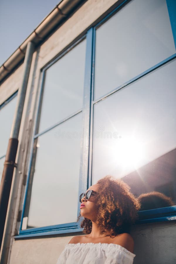Belle femme africaine s'asseyant dehors et regardant loin photo stock Belle femme africaine s'asseyant dehors et regardant loin photo stock