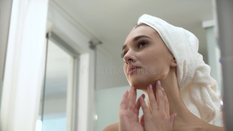 Belle femme après la douche regardant dans le miroir la salle de bains banque de vidéos