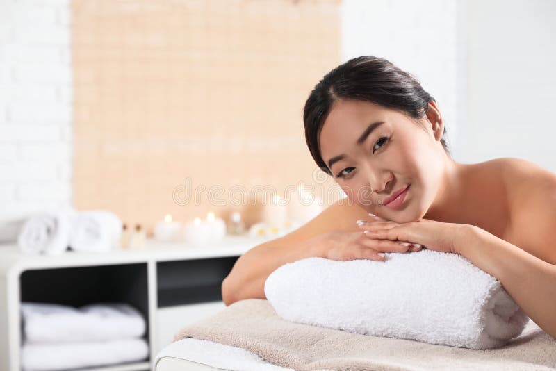 Belle femme asiatique se trouvant sur la table de massage dans le salon de station thermale images libres de droits Belle femme asiatique se trouvant sur la table de massage dans le salon de station thermale images libres de droits