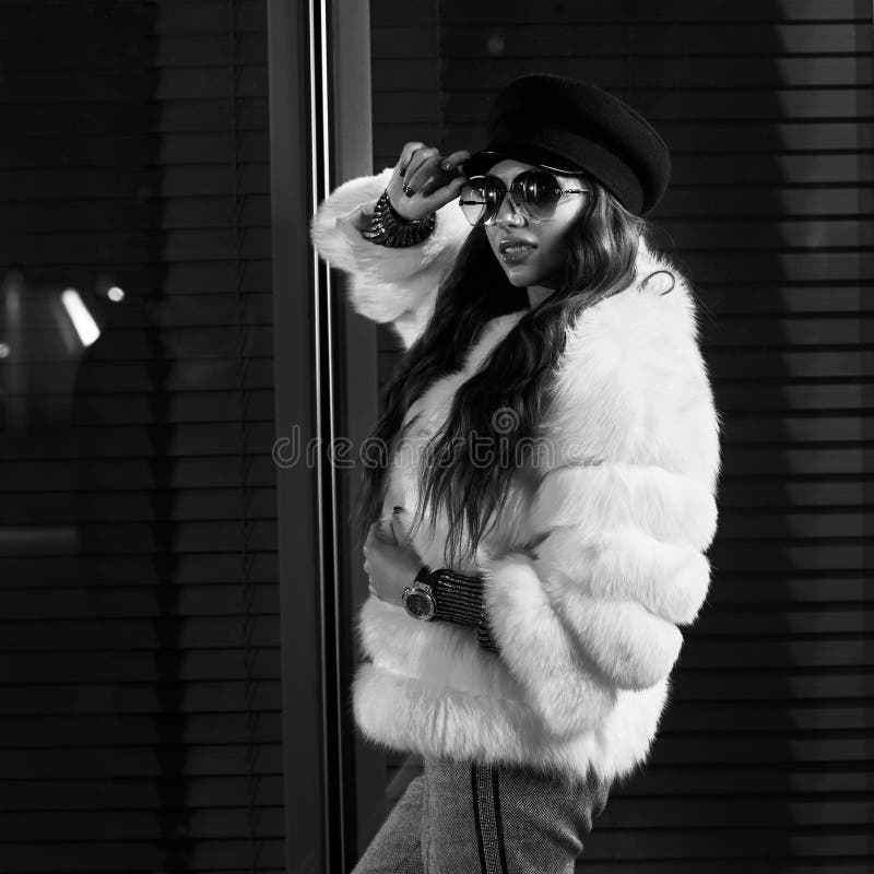 Belle femme aux cheveux longs dans le chapeau, les lunettes de soleil et le coa blanc de fourrure photographie stock Belle femme aux cheveux longs dans le chapeau, les lunettes de soleil et le coa blanc de fourrure photographie stock