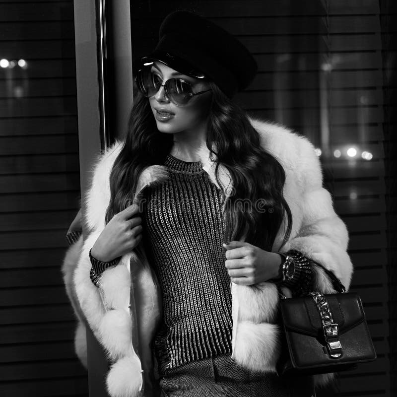 Belle femme aux cheveux longs dans le chapeau, les lunettes de soleil et le coa blanc de fourrure photos libres de droits Belle femme aux cheveux longs dans le chapeau, les lunettes de soleil et le coa blanc de fourrure photos libres de droits
