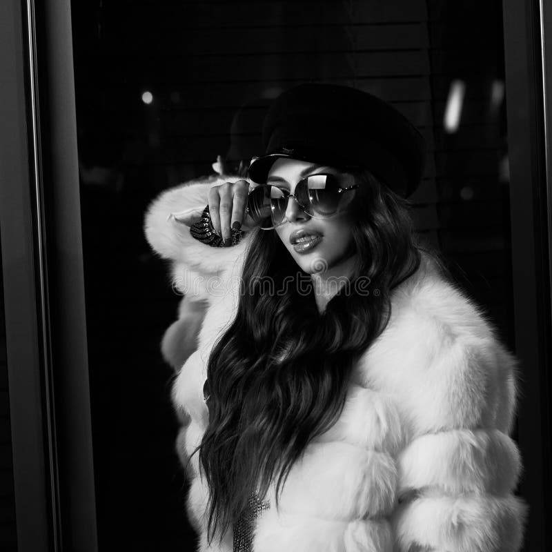 Belle femme aux cheveux longs dans le chapeau, les lunettes de soleil et le coa blanc de fourrure photos libres de droits Belle femme aux cheveux longs dans le chapeau, les lunettes de soleil et le coa blanc de fourrure photos libres de droits