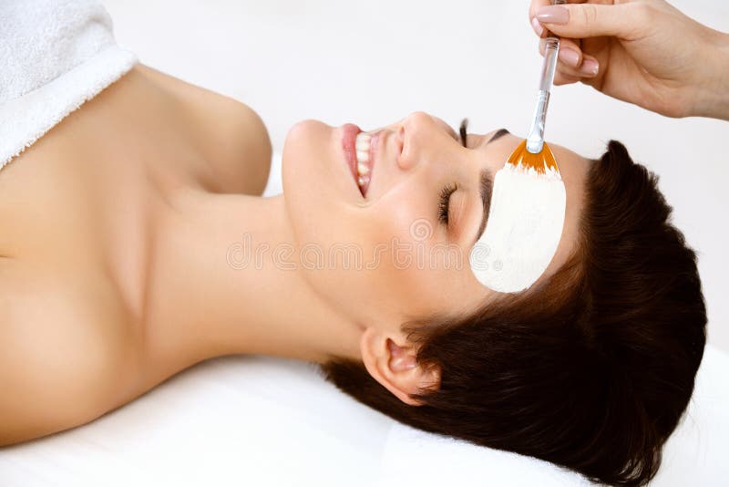 Belle femme avec le masque cosmétique sur le visage. La fille obtient le traitement photo stock Belle femme avec le masque cosmétique sur le visage. La fille obtient le traitement photo stock