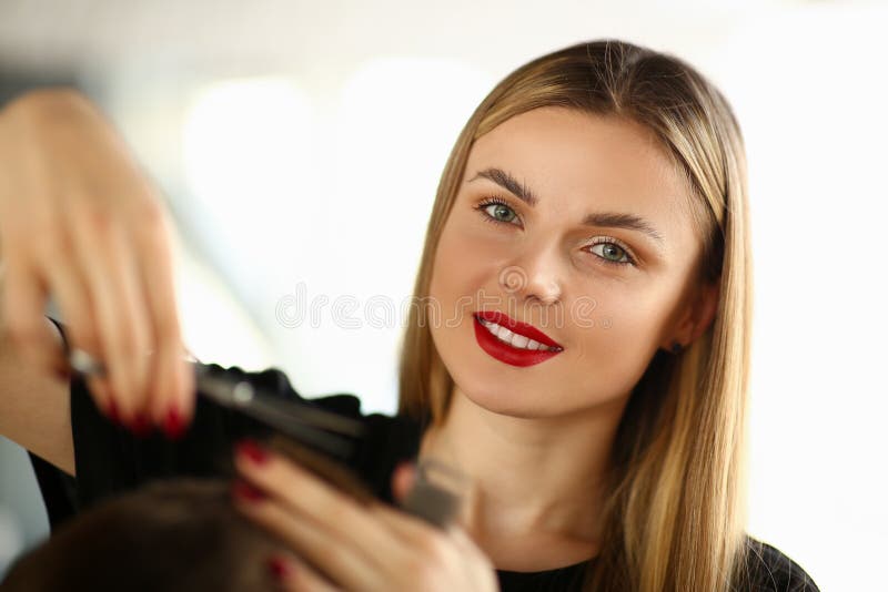 Belle femme coupant les cheveux masculins dans le salon de beauté images stock Belle femme coupant les cheveux masculins dans le salon de beauté images stock