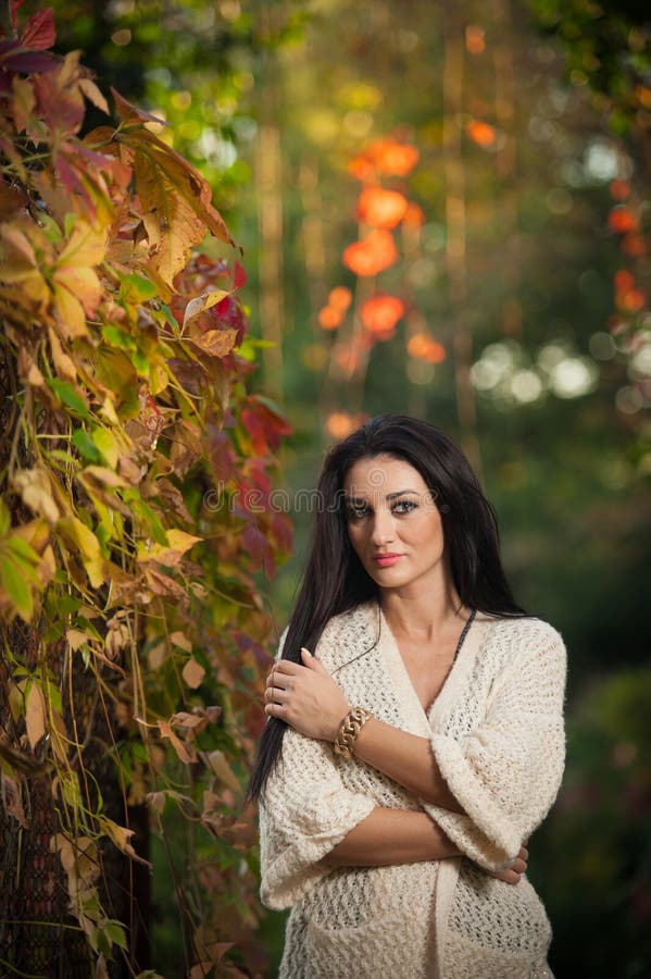 Belle femme dans la pose blanche en parc automnal Jeune femme de brune passant le temps en automne près d'un arbre dans la forêt photo libre de droits Belle femme dans la pose blanche en parc automnal Jeune femme de brune passant le temps en automne près d'un arbre dans la forêt photo libre de droits