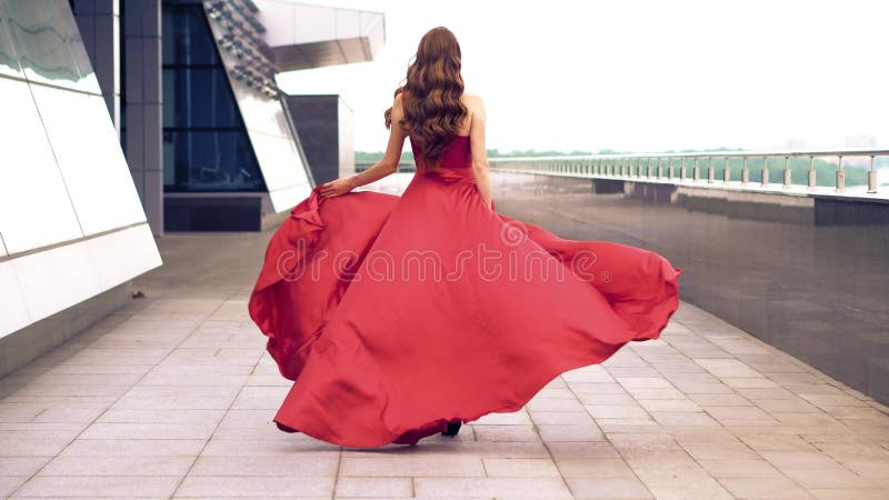 Belle femme dans la robe de flottement rouge