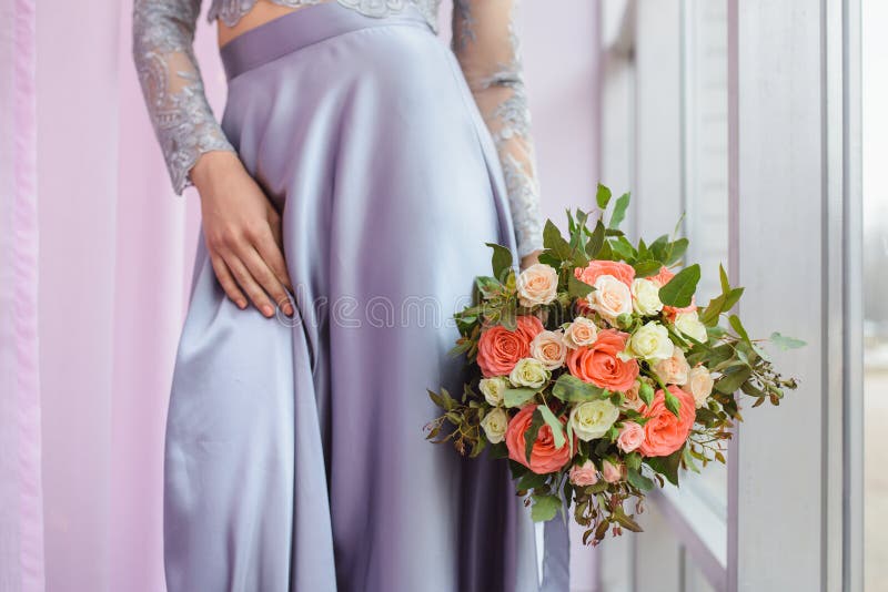 Belle femme dans une robe de prune tenant un bouquet des roses, pousse de détail de plan rapproché, foyer sur des fleurs photographie stock Belle femme dans une robe de prune tenant un bouquet des roses, pousse de détail de plan rapproché, foyer sur des fleurs photographie stock